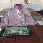 Table laid with pink runner, floral placemats, wine glasses in outdoor setting at Hap & Hop Padstal